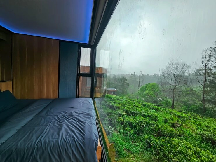 Durabilidad del hogar móvil en diferentes climas: lo que los compradores deben sabersunlit-tec Dormitorio moderno con gran ventana con vistas al exuberante paisaje verde en un día lluvioso